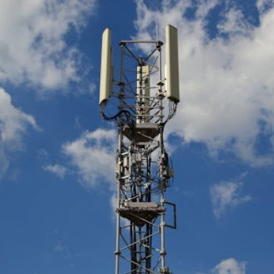 A tall cellular communication tower against a vivid blue sky, symbolizing modern technology.